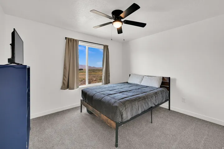 Spacious and bright bedroom with ceiling fan and neutral flooring.