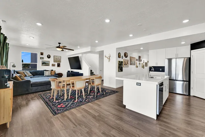 Open-concept living space featuring LVP flooring, recessed lighting, and a modern kitchen with a white island and stainless steel appliances
