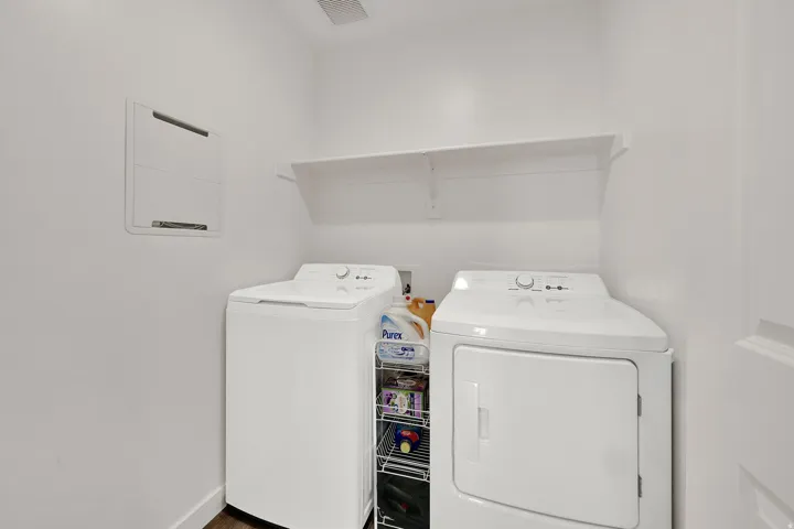 Dedicated laundry area featuring a white wall & shelf
