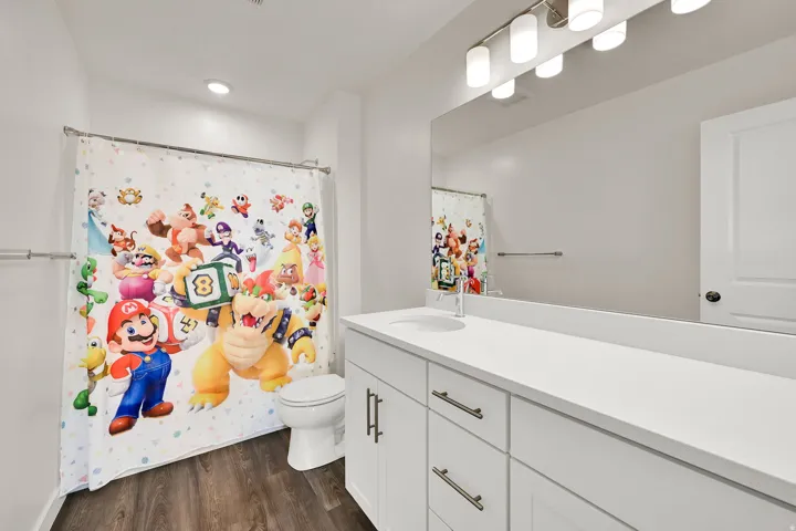 Bathroom featuring a white vanity with an integrated sink and brushed nickel hardware, a large wall-mounted mirror, and wood look LVP flooring