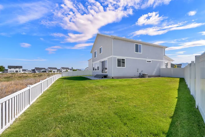 Expansive green lawn featuring white fencing and a gray exterior residence with white trim