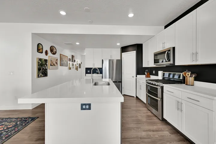 Open-concept kitchen featuring white cabinetry, light-toned countertops, and stainless steel appliances