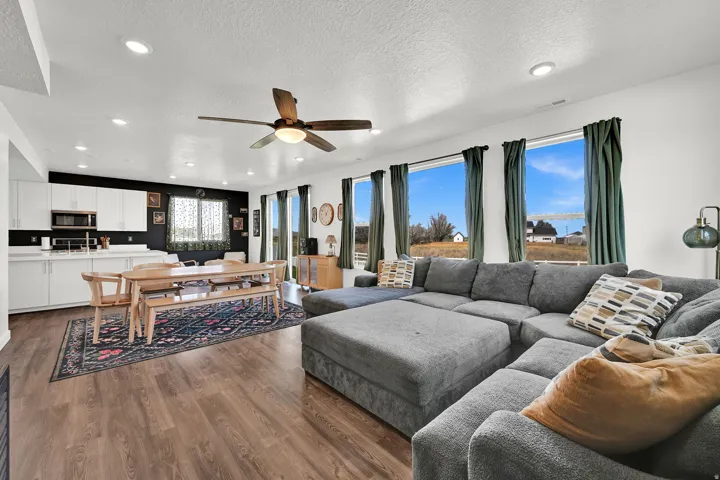 Spacious open-concept living area featuring LVP flooring, recessed lighting, and a ceiling fan