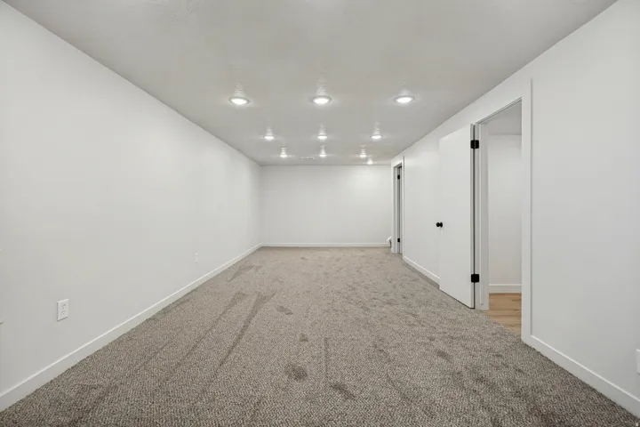 Spacious room featuring new carpeting, recessed ceiling lighting, crisp white walls, and contemporary white trim