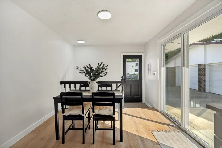 Bright dining area featuring hardwood-style flooring, a black paneled door with glass insert, and a large sliding glass door