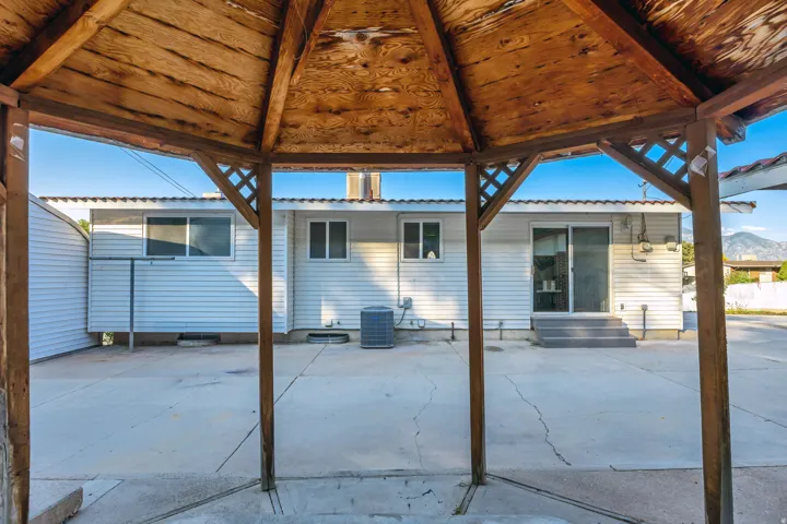 Expansive concrete patio area, ideal for outdoor gatherings, featuring a built-in wooden gazebo with lattice detailing