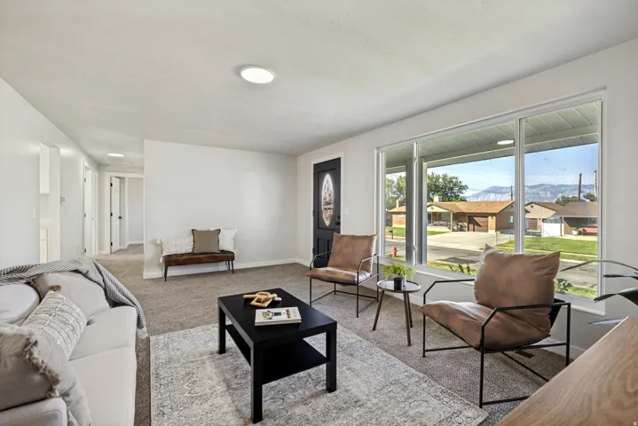 Bright living area featuring a large picture window, recessed lighting, and neutral carpeting