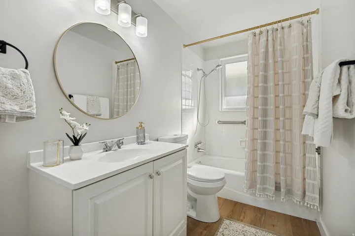 Bathroom featuring a white vanity with integrated sink, chrome faucet, and a large round mirror