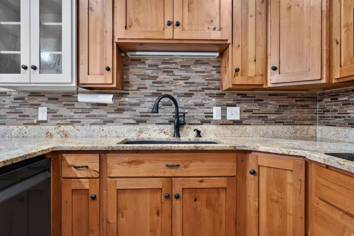 Kitchen featuring light wood cabinetry, a dark sink, and a black faucet