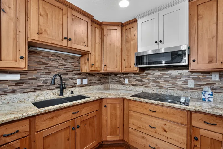 Corner kitchen featuring wood-finish cabinetry, granite countertops, and a tiled backsplash