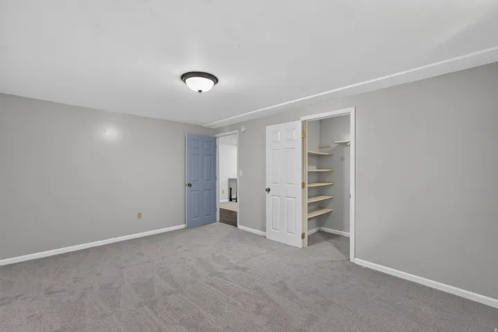 Carpeted room featuring light gray walls, a white ceiling with a flush-mount light fixture, and white trim