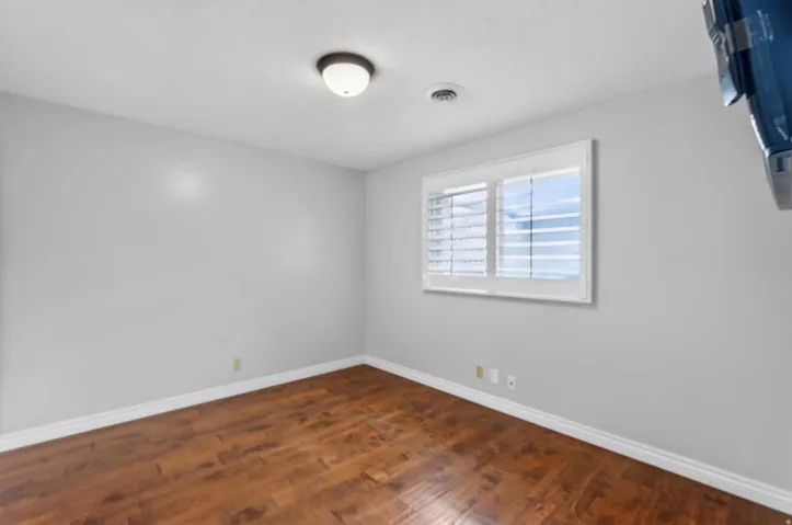 Room featuring wood-finish flooring, light grey walls, and white trim