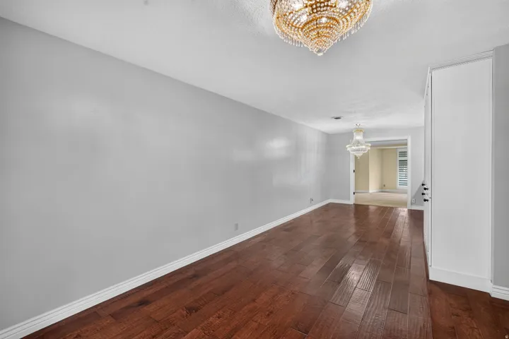Interior space featuring wood-finish flooring, light gray walls, white baseboards, and a prominent crystal chandelier