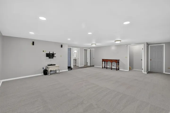 Open-concept room featuring light gray carpeting, recessed ceiling lighting, and multiple door access points
