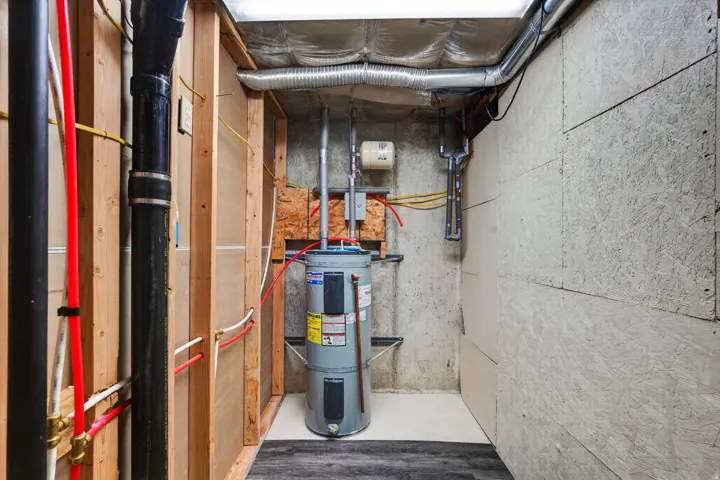 Utility area featuring a water heater, exposed piping, ductwork, and structural wood framing