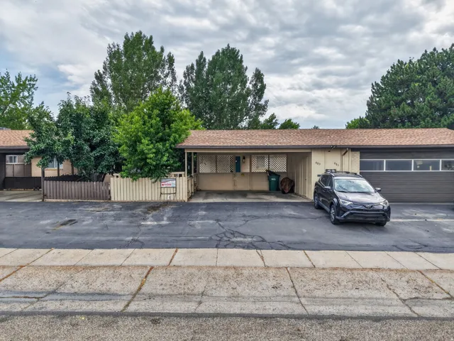 Single-story facade featuring a brown shingle roof, attached garage with horizontal window accents, and a covered carport