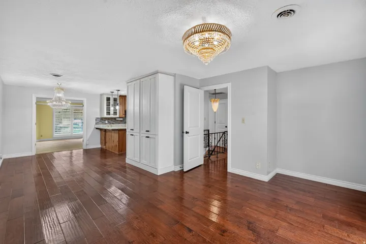 Hardwood-style flooring extends throughout this interior space, illuminated by an ornate ceiling chandelier