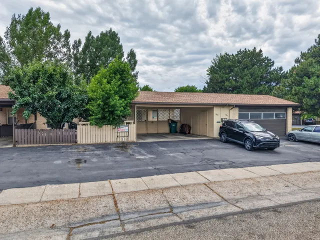 Single-story exterior with a covered carport, attached garage, and mature landscaping