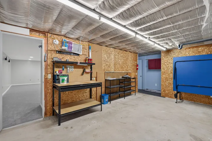 Versatile basement space featuring cork-finished accent walls, polished concrete flooring, and ample storage solutions with industrial-style shelving units