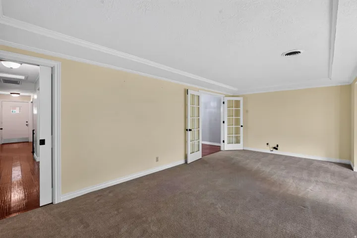 Spacious room featuring neutral carpeting, light-colored walls, and classic crown molding