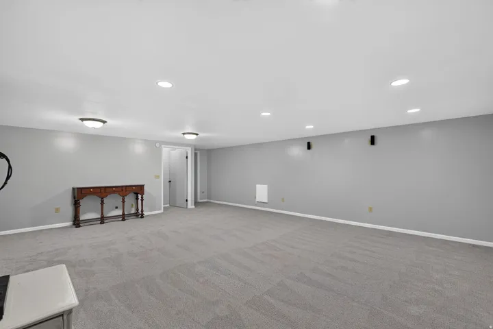 Spacious room featuring light gray walls, light gray carpet flooring, recessed lighting, and flush-mount ceiling fixtures