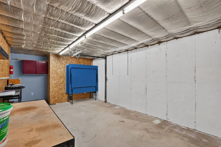 Unfinished basement space featuring exposed concrete flooring, white panel walls, and an insulated ceiling