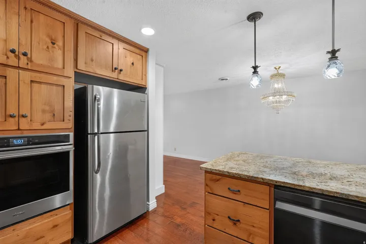 Kitchen featuring wood cabinetry, stainless steel appliances, and a light-toned stone countertop