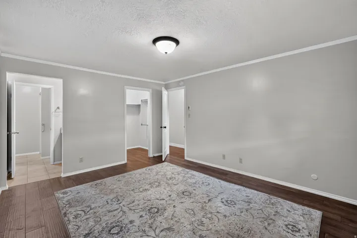 Spacious room featuring wood-finish flooring, light grey walls, white trim, and a flush-mount ceiling light