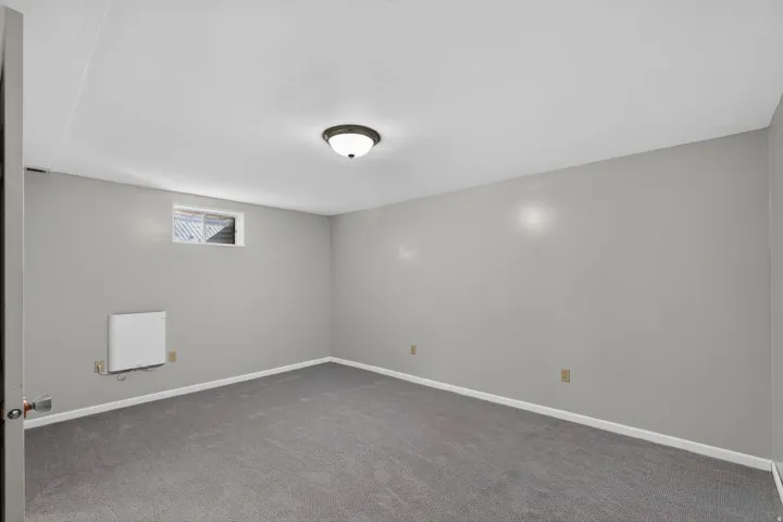Carpeted room featuring light gray walls, a flush-mount ceiling light fixture, a window with horizontal blinds, and baseboard trim