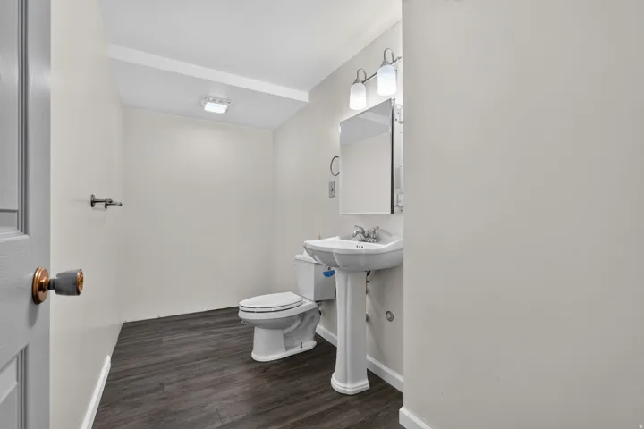 Bathroom featuring wood-finish flooring, a white pedestal sink, and a toilet