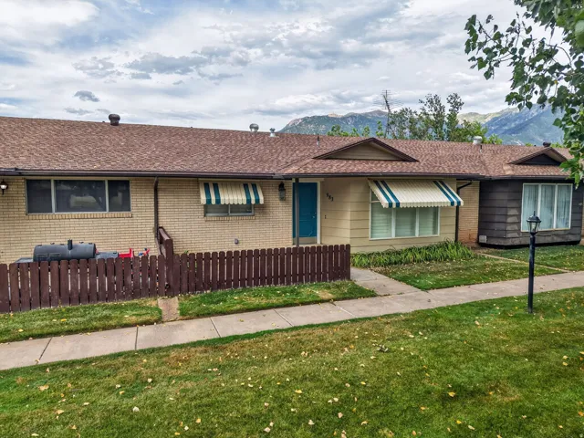 Ranch-style exterior featuring a brown shingle roof, a mix of light brick and horizontal siding, and striped awnings over windows