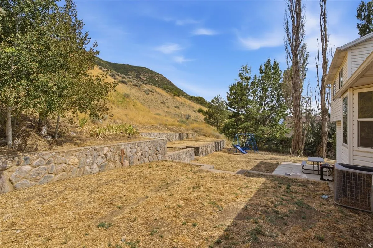 Terraced stone retaining walls defining the rear yard, featuring a concrete patio pad and a white siding exterior