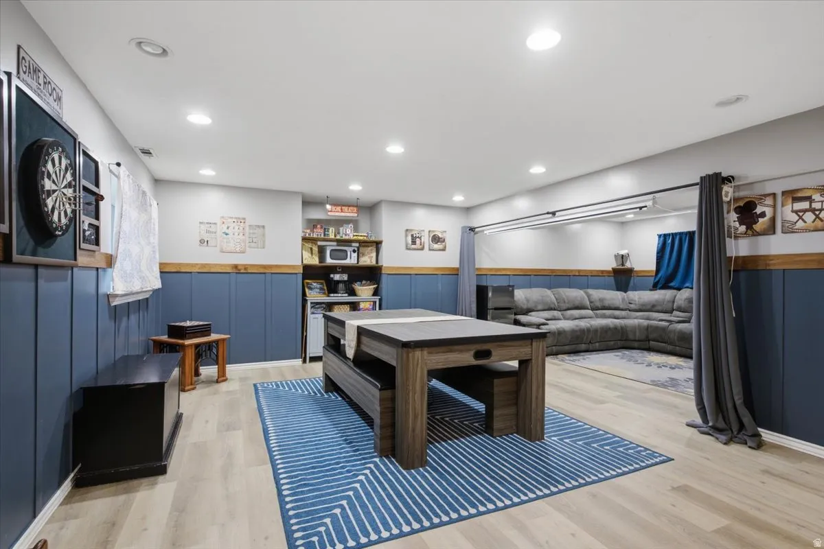 Spacious lower-level area featuring recessed lighting, light wood-finish flooring, and blue wainscoting with wood trim