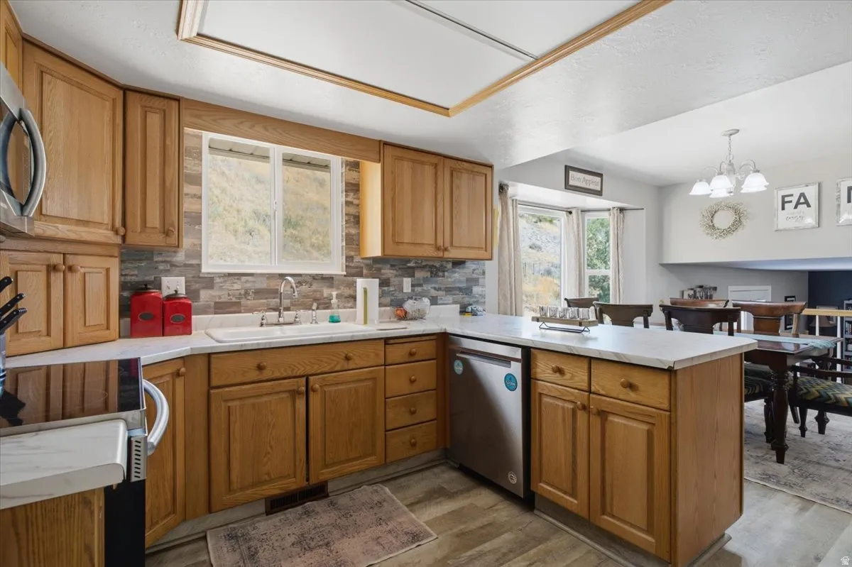 Kitchen featuring wood cabinetry, light-toned countertops, a stacked stone-look backsplash, and stainless steel appliances. Mountain Views from windows.