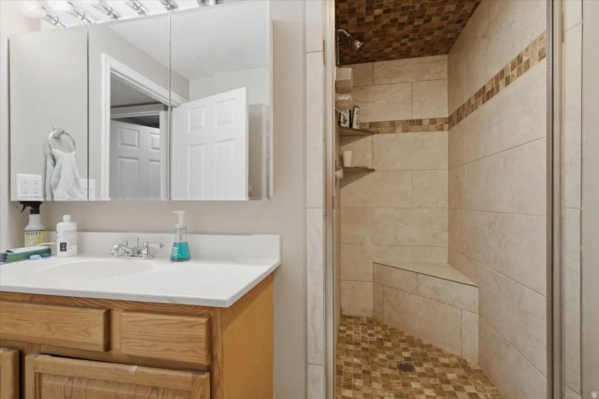 Walk-in shower with full wall tiling, textured ceiling and floor tiling, and a built-in bench