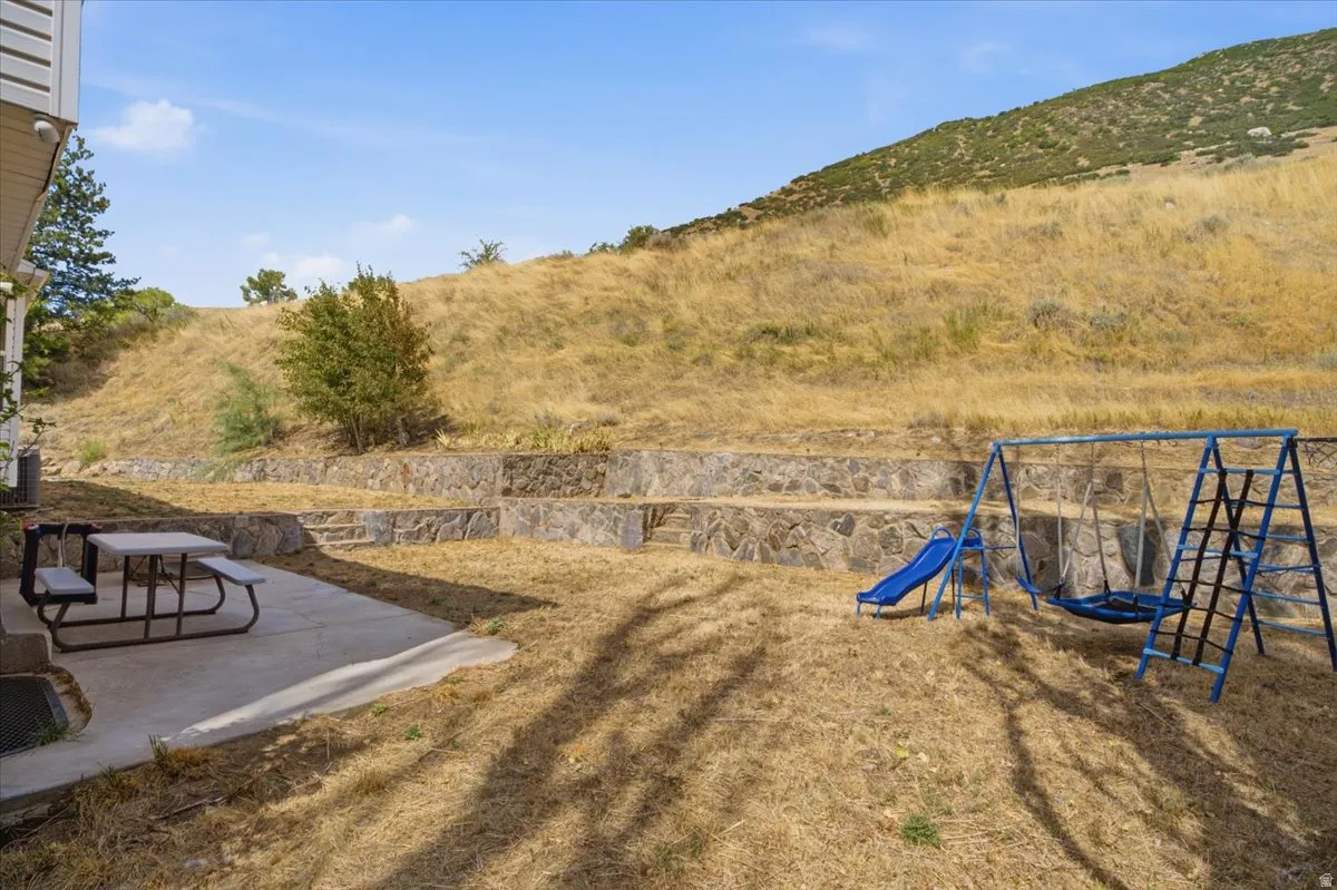 Expansive outdoor space featuring a concrete patio, tiered retaining walls, and a gorgous mountain views.