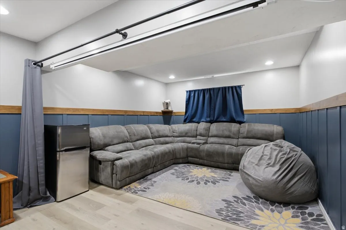 Spacious recreational area featuring plank flooring, recessed lighting, and a window with blue drapery