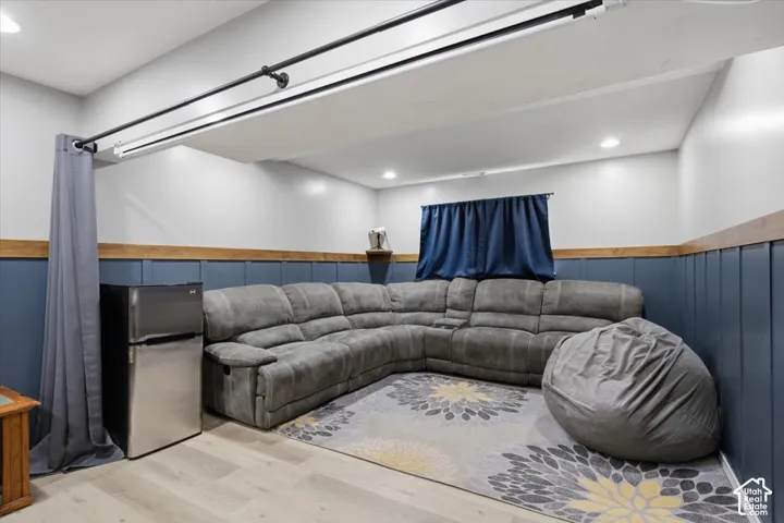 Spacious recreational area featuring plank flooring, recessed lighting, and a window with blue drapery