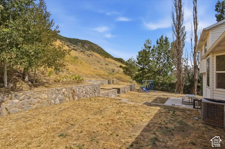 Terraced stone retaining walls defining the rear yard, featuring a concrete patio pad and a white siding exterior