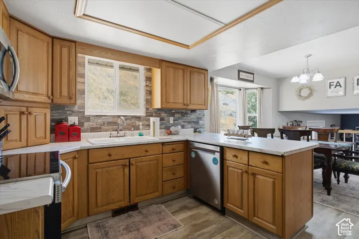 Kitchen featuring wood cabinetry, light-toned countertops, a stacked stone-look backsplash, and stainless steel appliances. Mountain Views from windows.