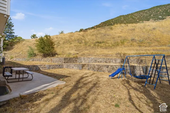 Expansive outdoor space featuring a concrete patio, tiered retaining walls, and a gorgous mountain views.