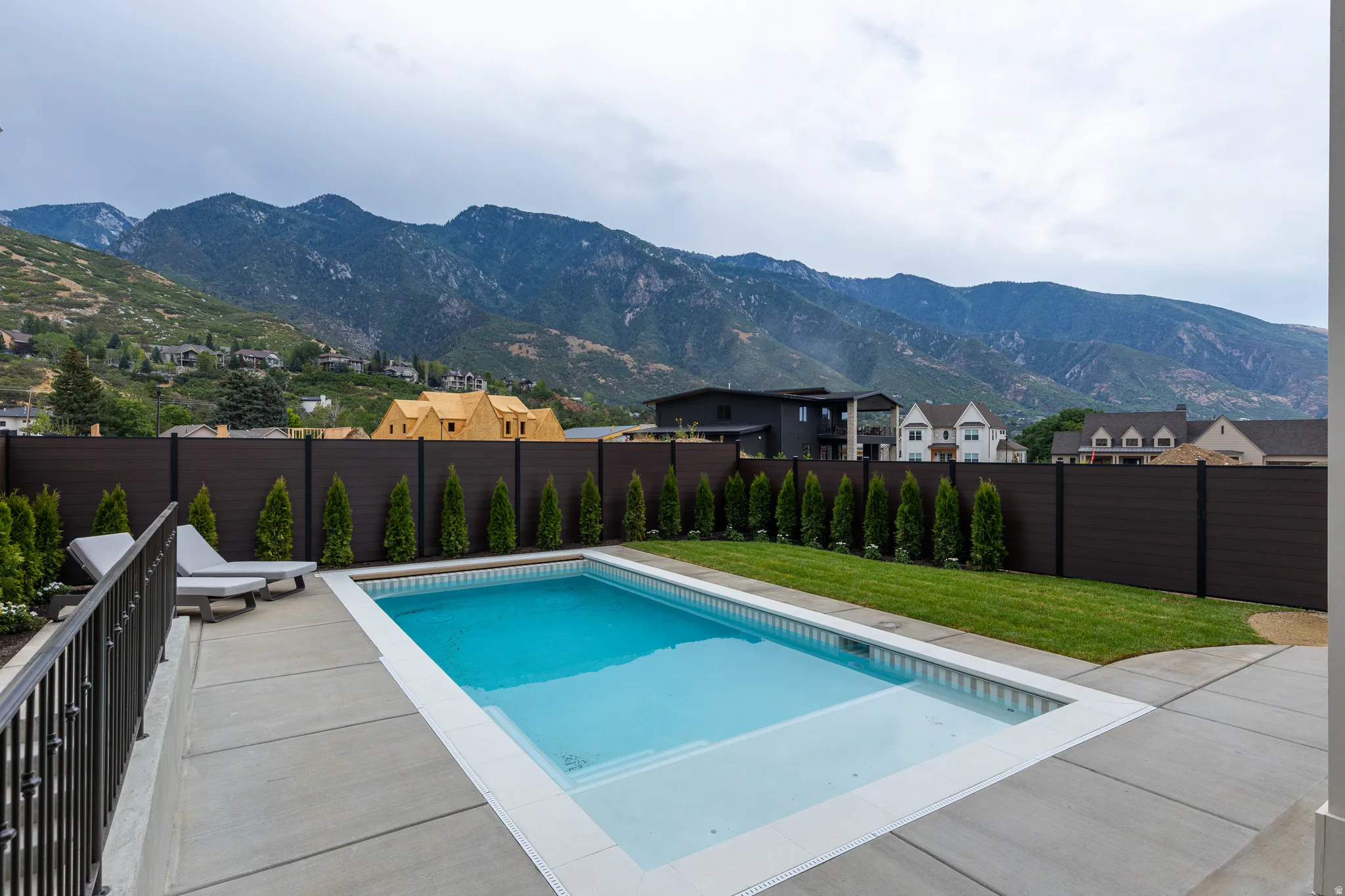 Rectangular swimming pool with integrated steps, surrounded by concrete patio and a manicured lawn