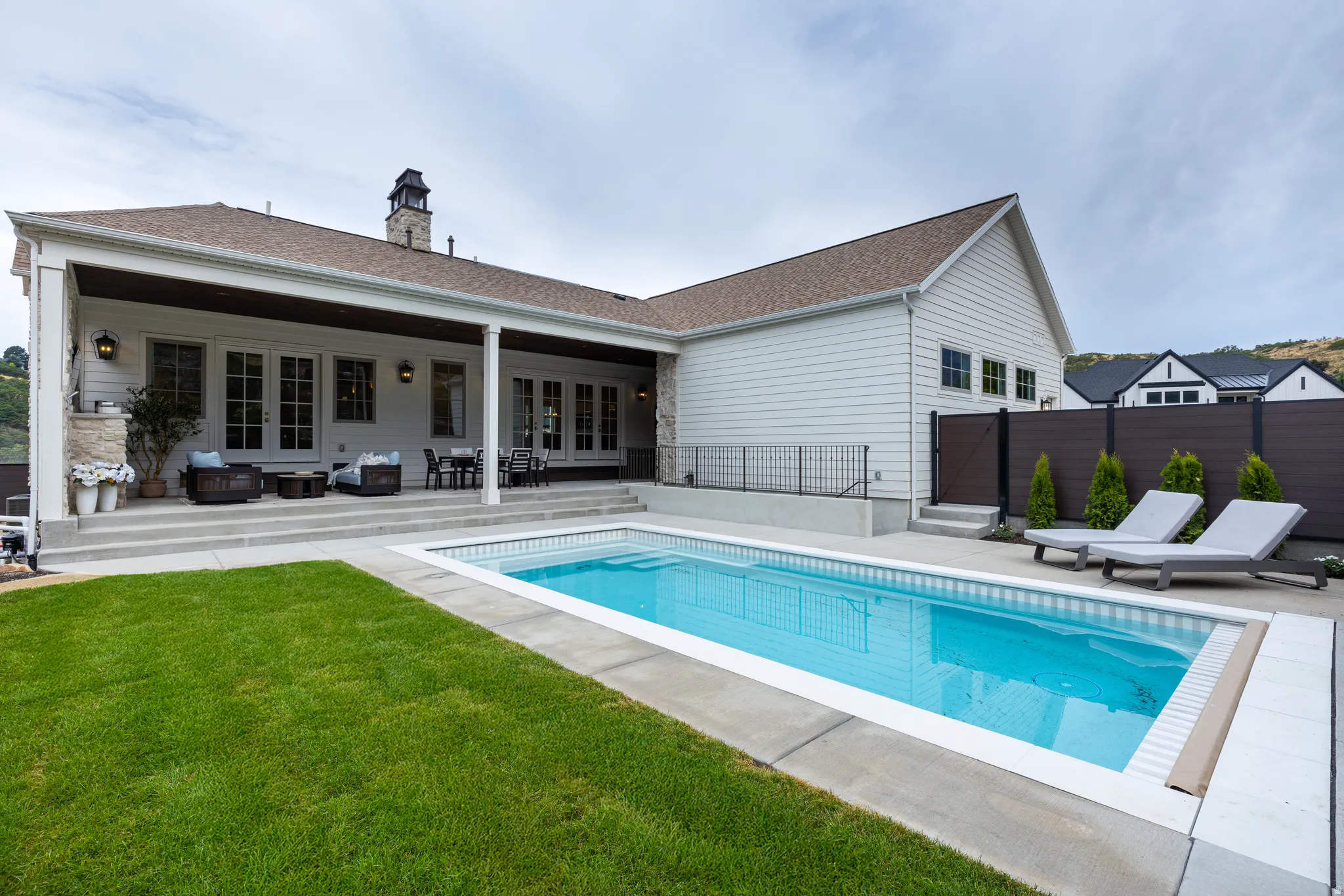 Rear exterior with a rectangular swimming pool, concrete surround, and grassy area