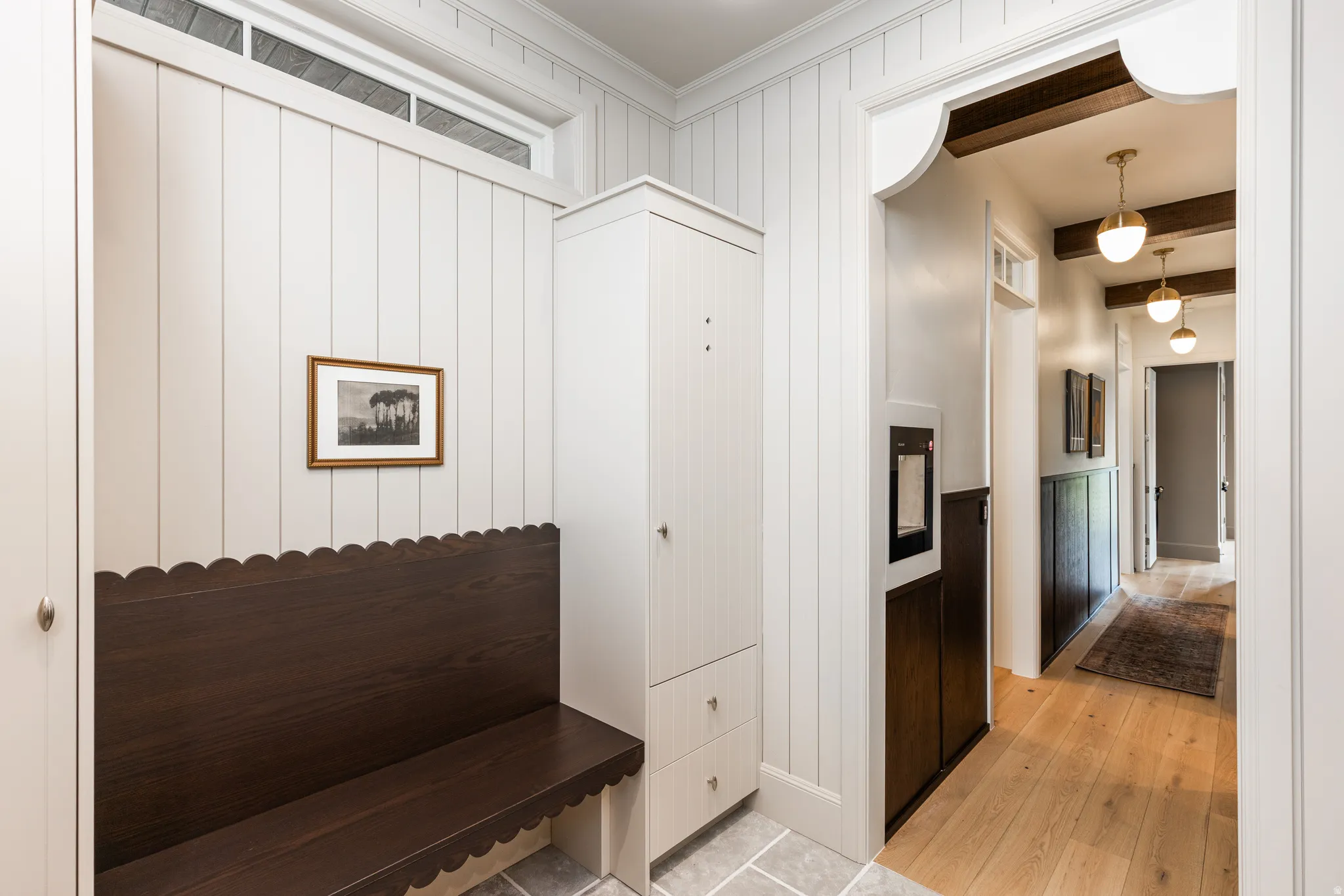 Entryway featuring vertical shiplap paneling, a dark wood built-in bench, a built-in storage cabinet with drawers, and transom window