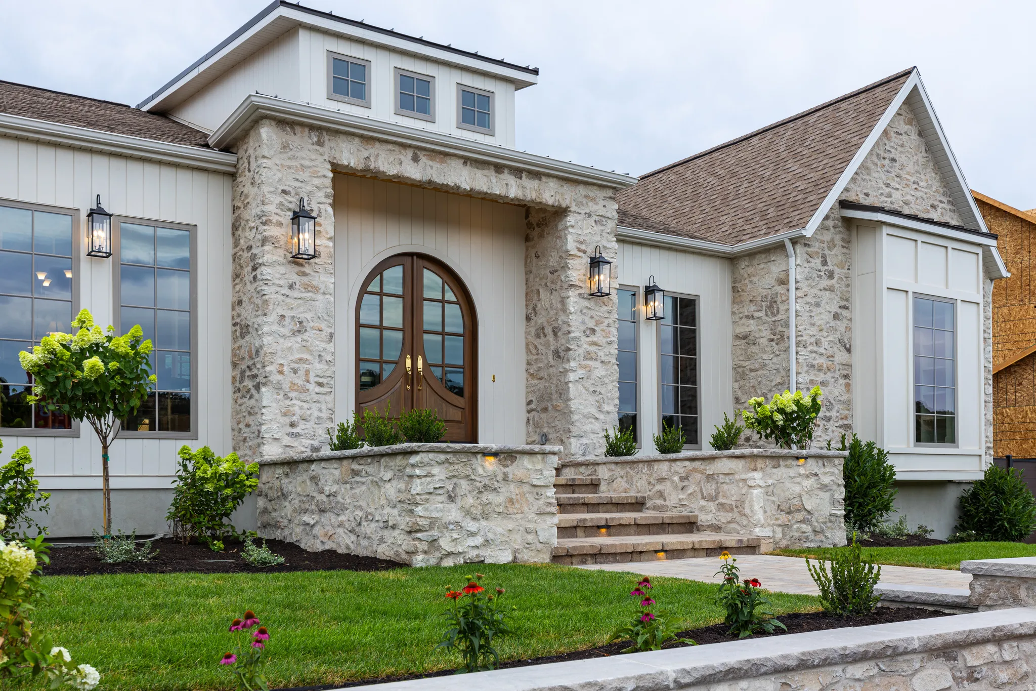 Stone and board-and-batten exterior featuring an arched double-door entry