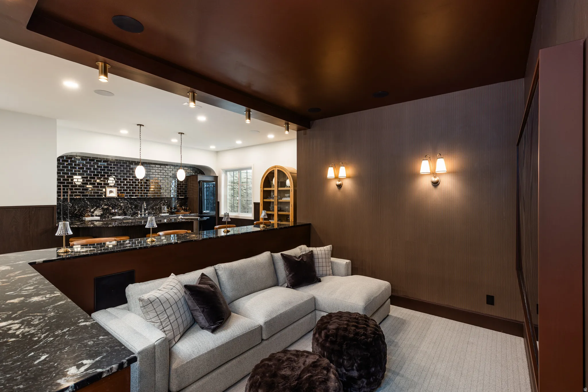 Entertainment space featuring a built-in wet bar with dark granite countertops and subway tile backsplash