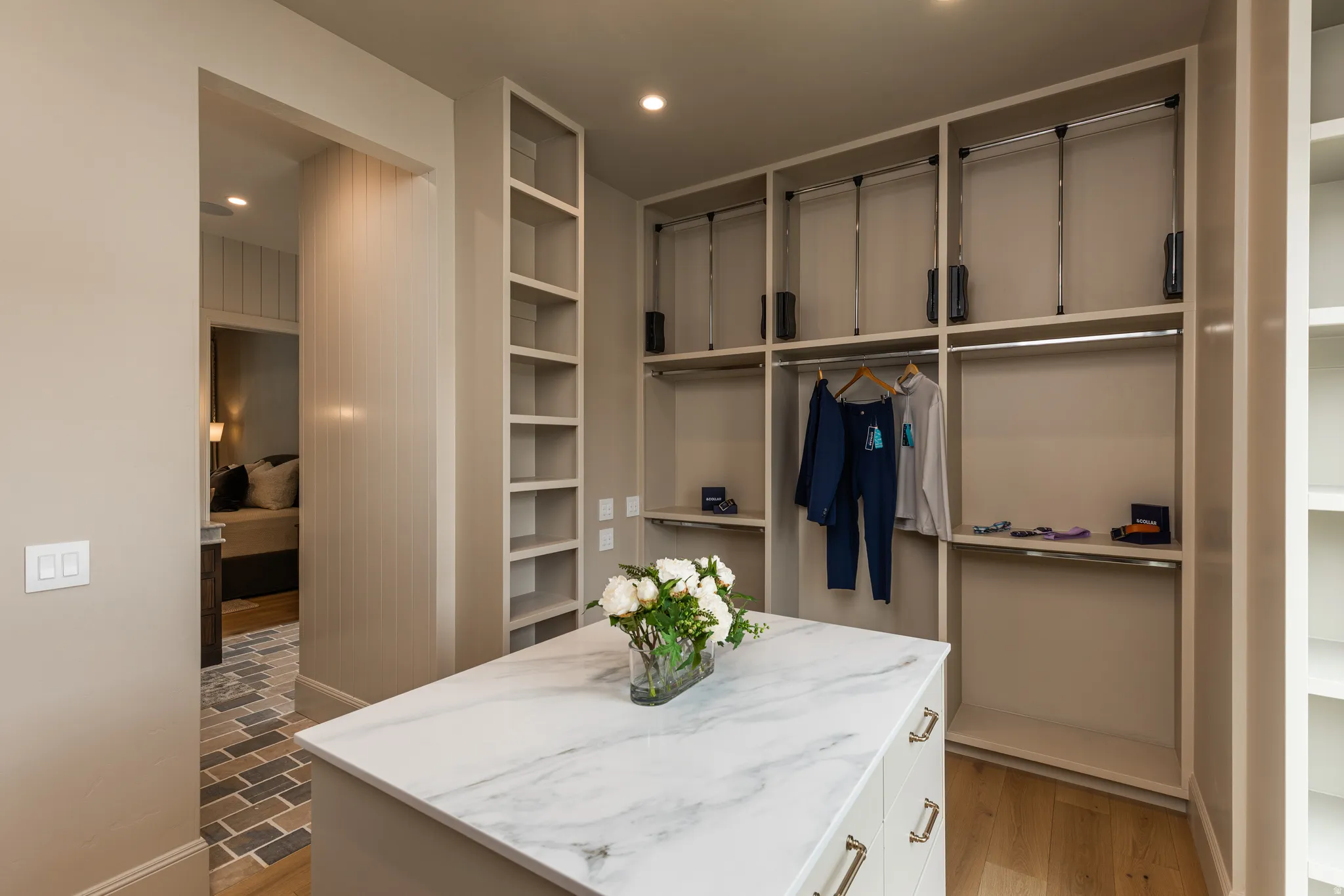 Custom closet featuring a large stone-finish island with drawers and chrome hardware