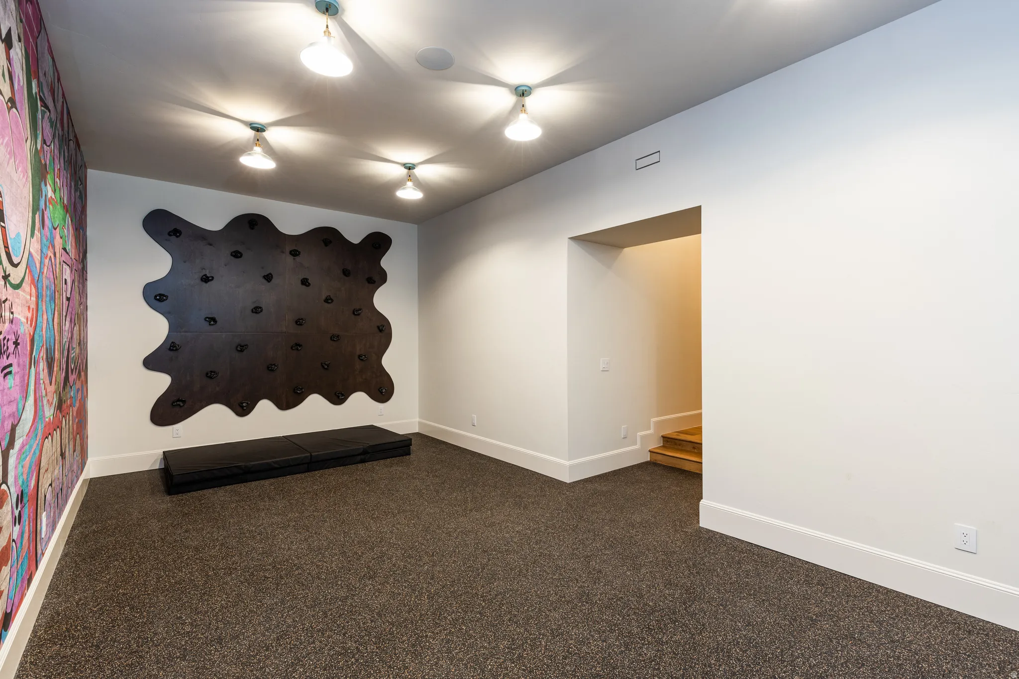 Recreation room featuring a climbing wall with multiple holds, textured wall covering, and recessed ceiling lighting