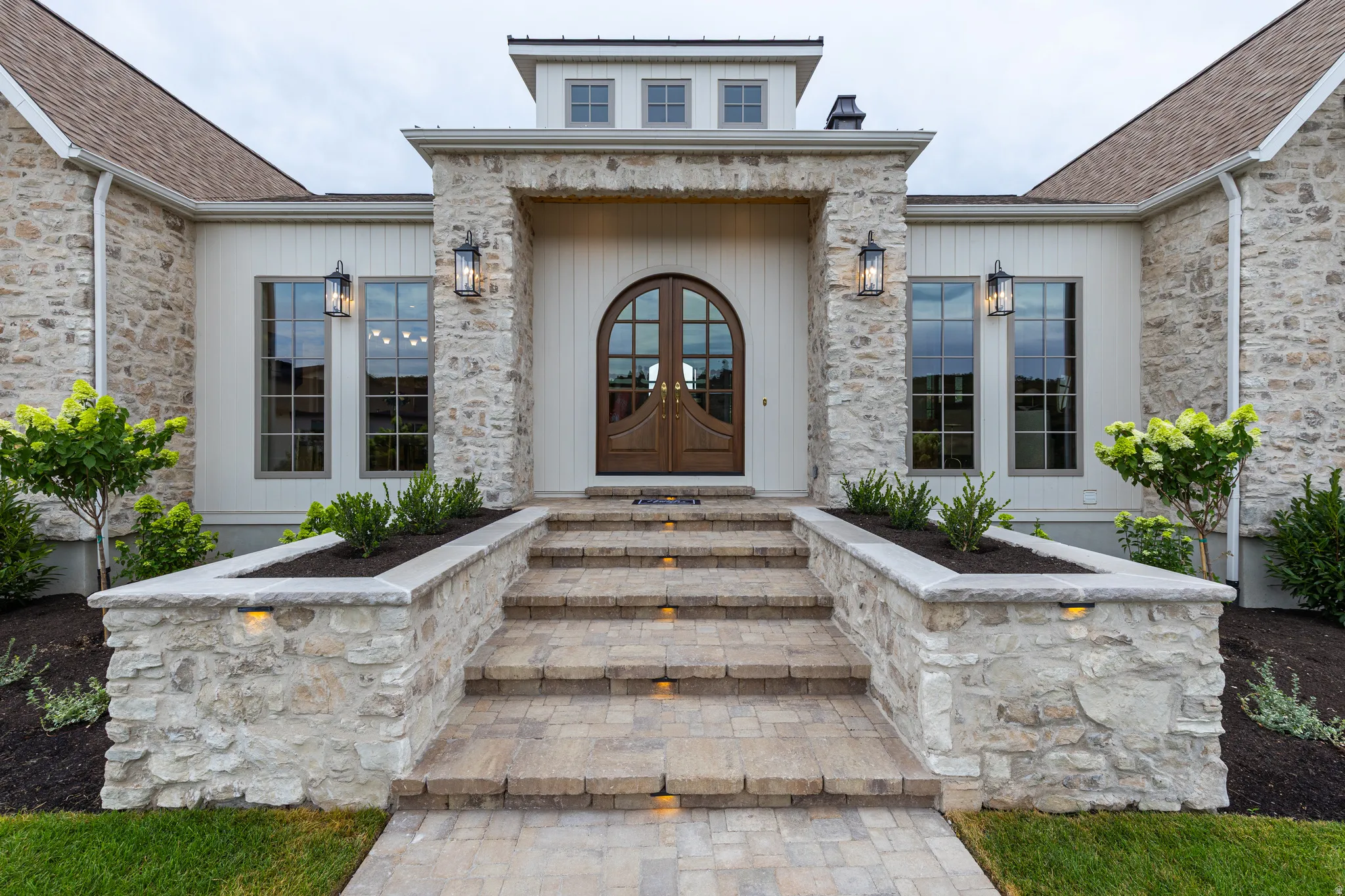 Stone and board-and-batten exterior with an arched wood-panel entry door