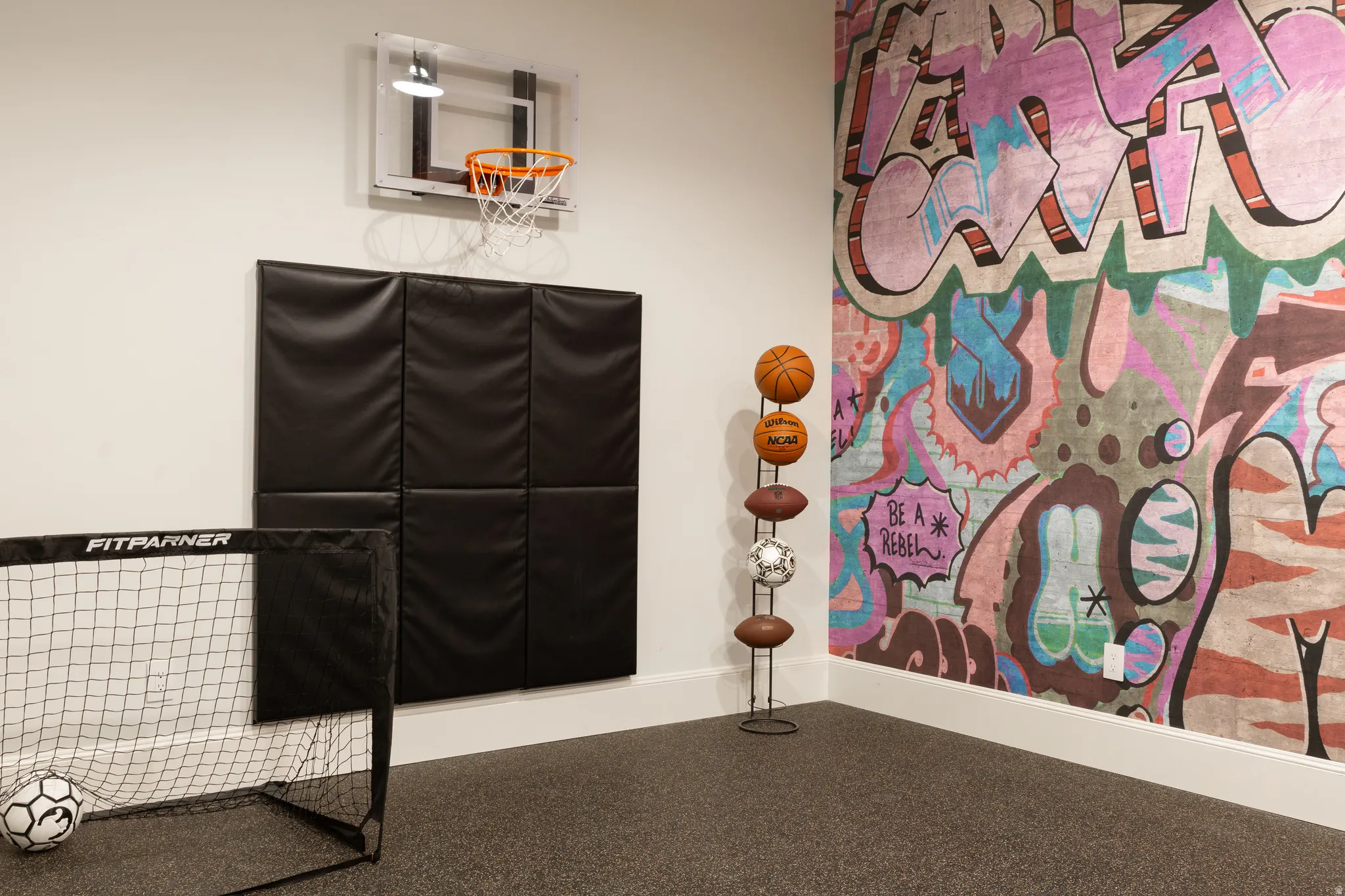 Wall-mounted basketball hoop, wall padding, graphic accent wall, and low-pile carpet flooring